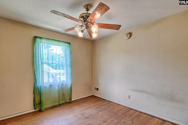 spare room featuring a textured ceiling, ceiling fan, light wood-style flooring, and visible vents