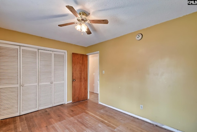 unfurnished bedroom with baseboards, ceiling fan, wood finished floors, and a closet