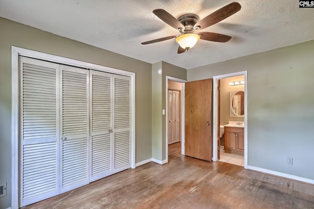 unfurnished bedroom with a sink, baseboards, a closet, and wood finished floors