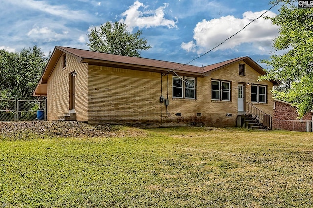 rear view of property with entry steps, fence, a lawn, and crawl space