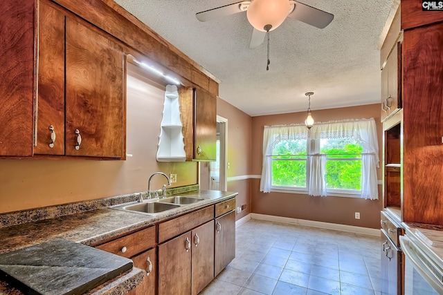 kitchen featuring brown cabinets, ceiling fan, a sink, a textured ceiling, and pendant lighting
