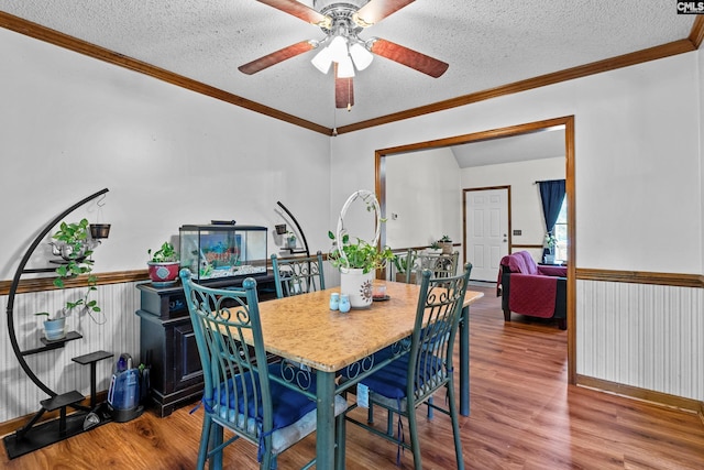 dining room with crown molding, a textured ceiling, a ceiling fan, and wood finished floors