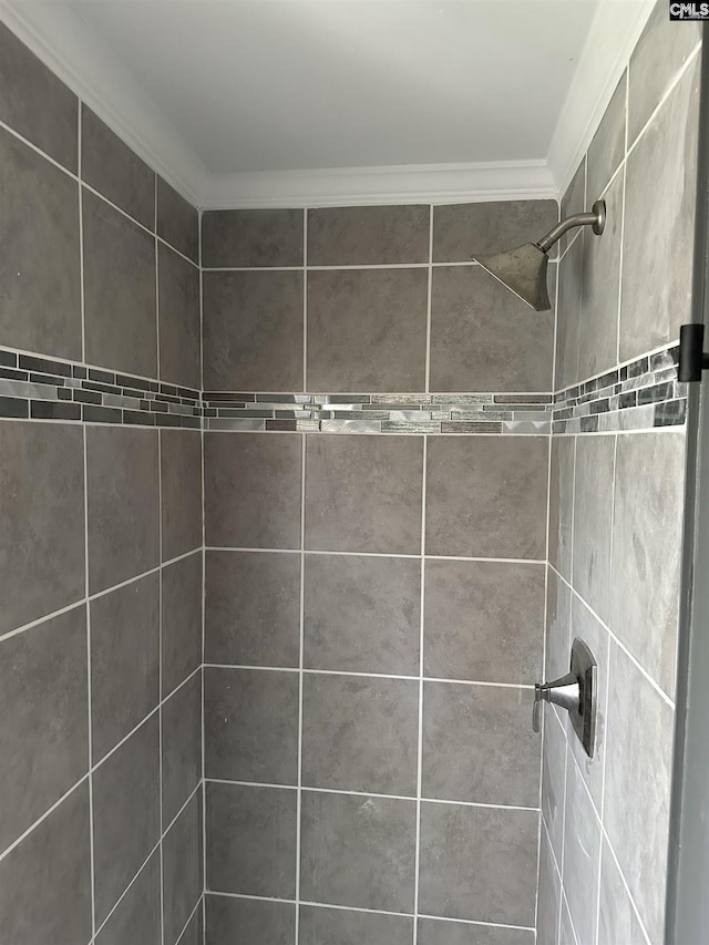full bathroom featuring a tile shower and ornamental molding