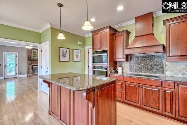 121 Cove View Dr, Irmo, SC 29063 - kitchen with crown molding, a fireplace, black electric stovetop, stainless steel double oven, and custom range hood