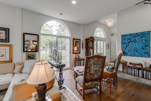 living room featuring a wealth of natural light, visible vents, wood finished floors, and a high ceiling
