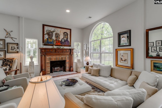 living area featuring recessed lighting, a brick fireplace, and visible vents
