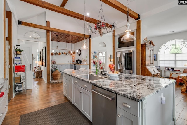 kitchen with gray cabinets, stainless steel appliances, beamed ceiling, and a sink
