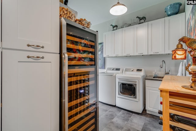laundry area with washer and dryer, a sink, cabinet space, and beverage cooler