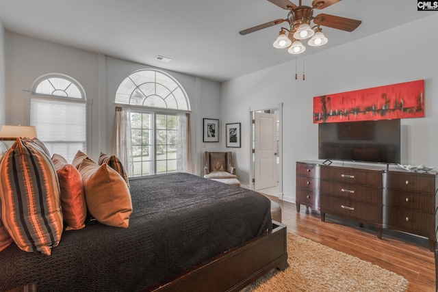 bedroom with ceiling fan, visible vents, and wood finished floors