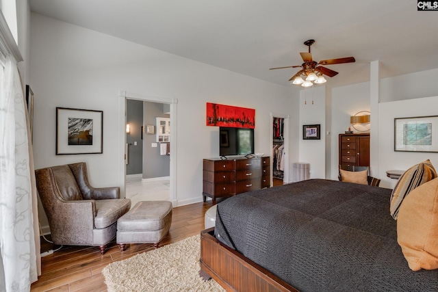 bedroom with a closet, ensuite bath, a walk in closet, baseboards, and light wood-style floors