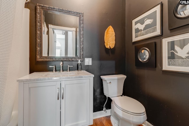 full bathroom featuring toilet, baseboards, vanity, and wood finished floors