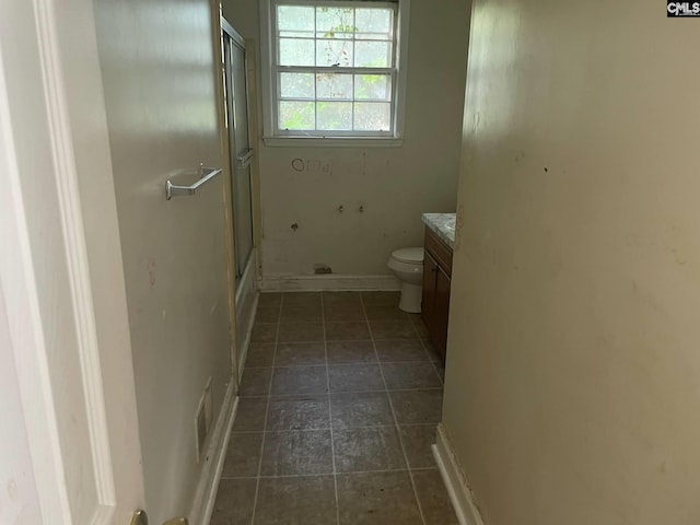 full bathroom with toilet, baseboards, a shower with door, and vanity