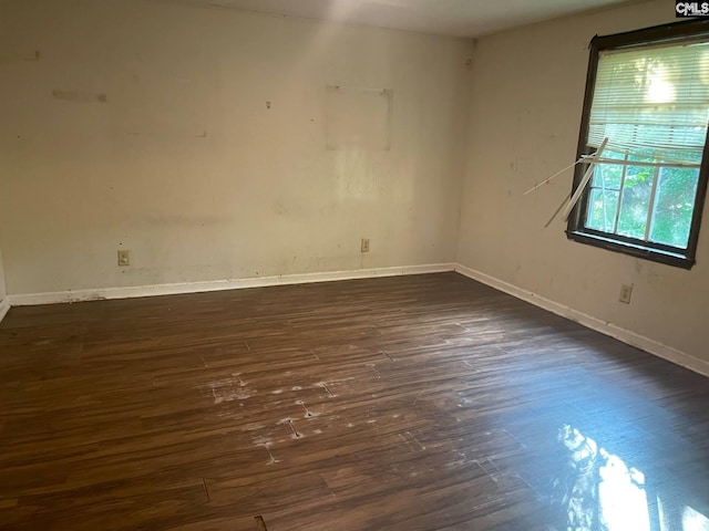 spare room featuring baseboards and dark wood-style floors