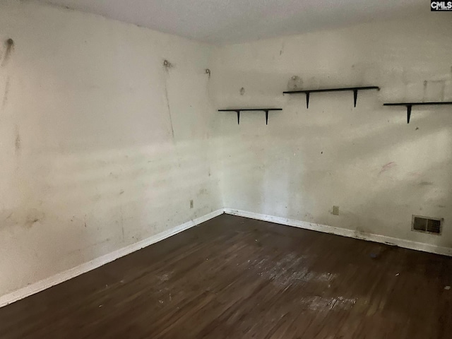 unfurnished room with baseboards, visible vents, and wood finished floors