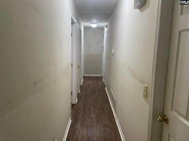 hall featuring attic access, visible vents, dark wood-style flooring, and baseboards