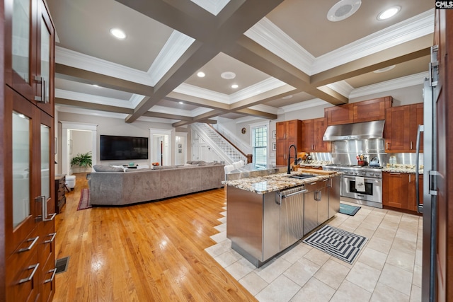 kitchen featuring beamed ceiling, open floor plan, under cabinet range hood, a sink, and appliances with stainless steel finishes