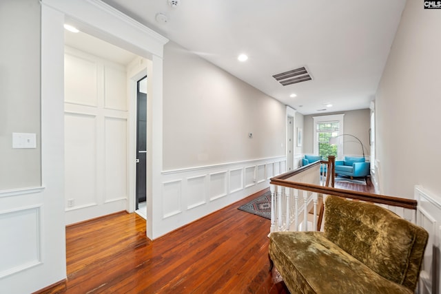 hallway featuring wainscoting, a decorative wall, hardwood / wood-style floors, recessed lighting, and visible vents
