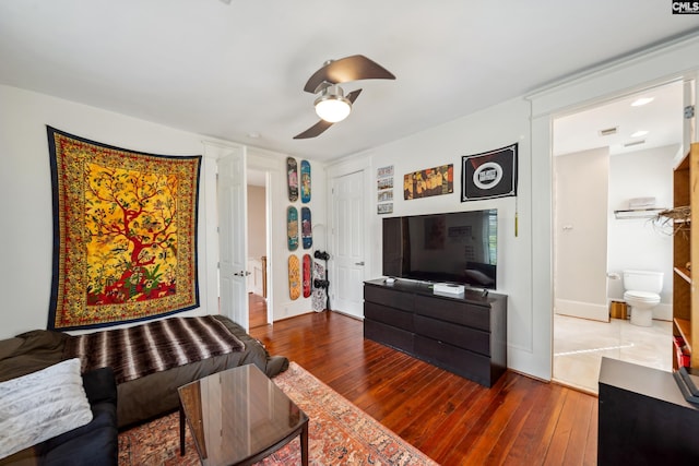 living area with baseboards, a ceiling fan, and hardwood / wood-style flooring