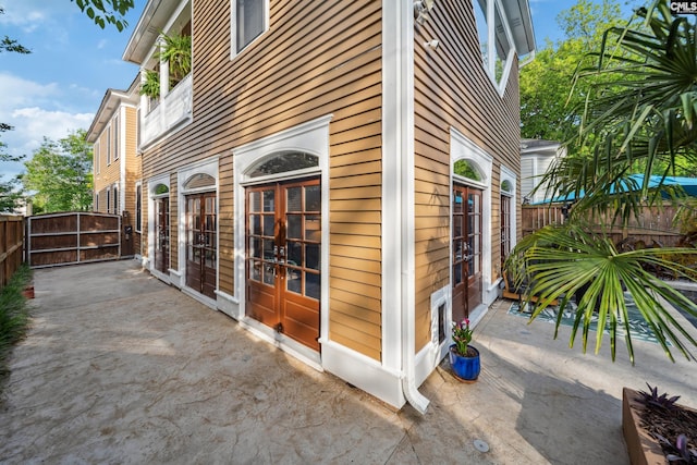 view of side of property featuring a patio, a gate, fence, and french doors