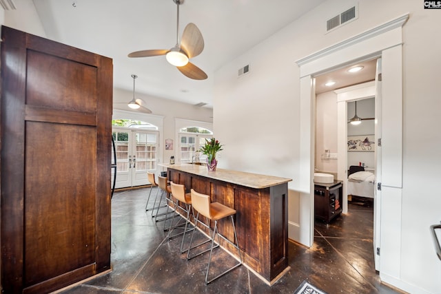 bar featuring ceiling fan, visible vents, concrete floors, and french doors