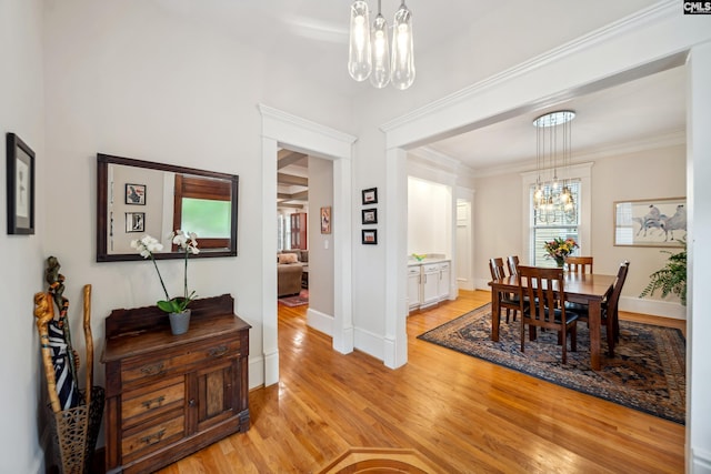dining room with baseboards, a chandelier, ornamental molding, and light wood-style flooring