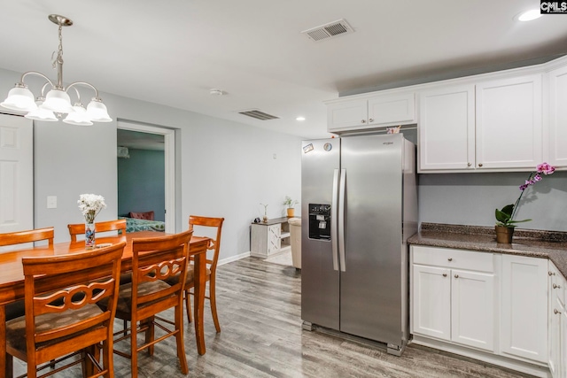 kitchen featuring white cabinets, light wood-type flooring, stainless steel fridge, and visible vents