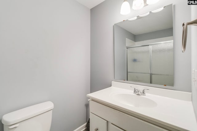 bathroom featuring vanity, toilet, baseboards, and a stall shower