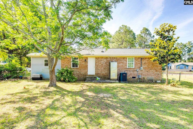 back of house with a yard, fence, cooling unit, and brick siding