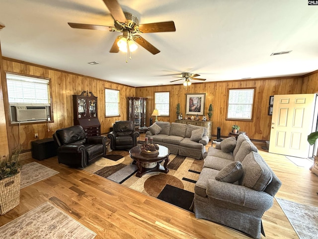 living area with wooden walls, cooling unit, plenty of natural light, and visible vents