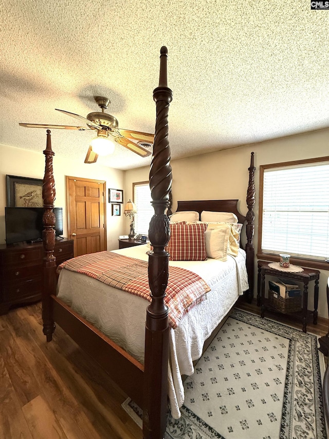 bedroom featuring a textured ceiling, wood finished floors, and multiple windows