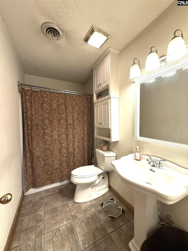 bathroom featuring a textured ceiling, baseboards, toilet, and visible vents