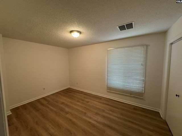 unfurnished room with baseboards, visible vents, a textured ceiling, and wood finished floors