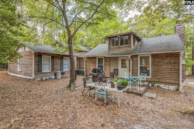 rear view of property featuring a chimney and roof with shingles