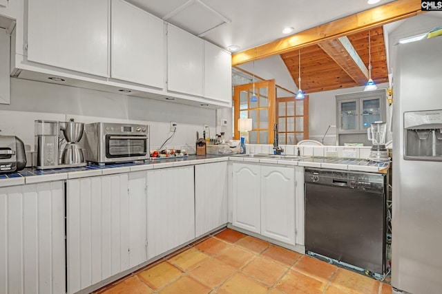kitchen with a sink, black dishwasher, tile countertops, stainless steel fridge, and vaulted ceiling with beams