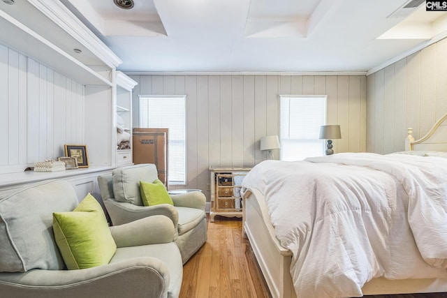 bedroom with wood walls, visible vents, and wood finished floors