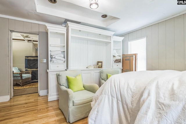 bedroom featuring a tray ceiling, light wood-type flooring, and a walk in closet