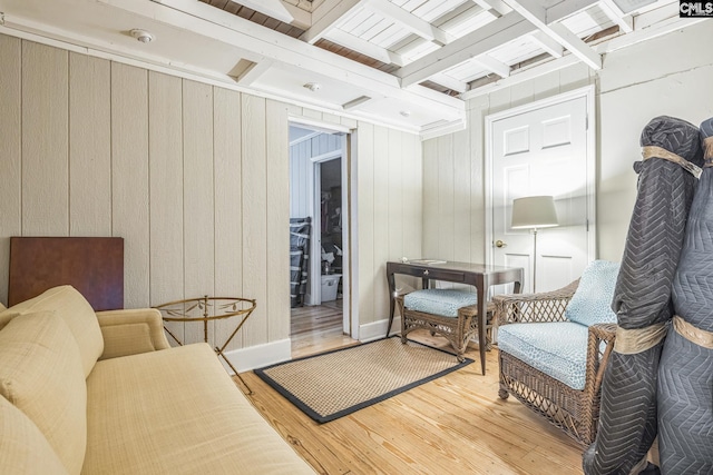 sitting room featuring light wood-style floors, wood walls, and beam ceiling