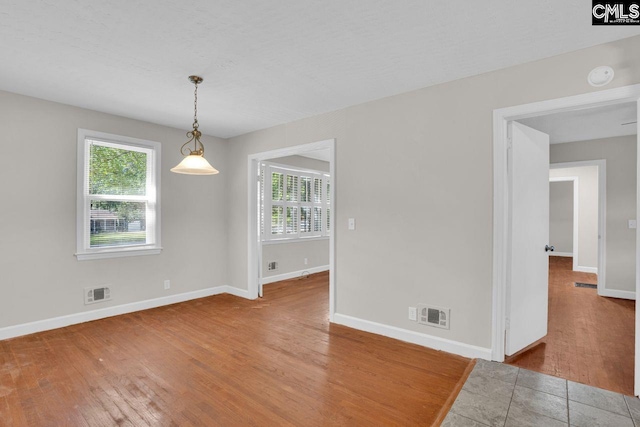 unfurnished dining area featuring plenty of natural light, visible vents, and wood finished floors