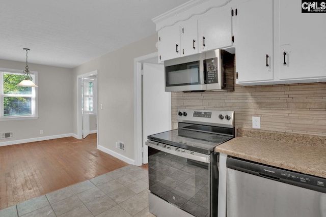 kitchen with stainless steel appliances, white cabinets, baseboards, light countertops, and decorative backsplash