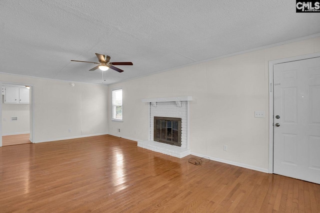 unfurnished living room featuring light wood-type flooring, a textured ceiling, a brick fireplace, and a ceiling fan