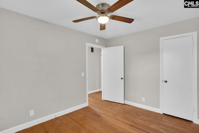 unfurnished bedroom featuring wood finished floors, baseboards, and ceiling fan