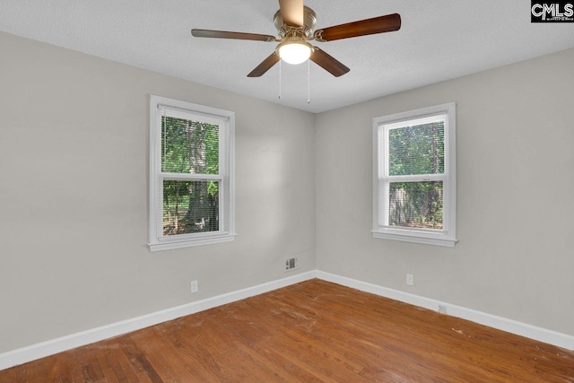 empty room with baseboards, visible vents, ceiling fan, and wood finished floors