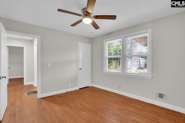 unfurnished bedroom featuring baseboards, a ceiling fan, visible vents, and wood finished floors
