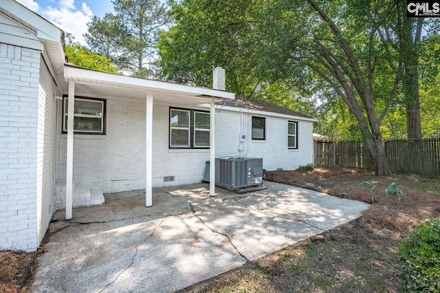 back of property featuring a chimney, brick siding, fence, central AC, and crawl space