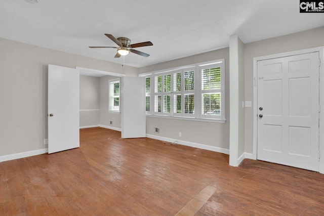 interior space with a ceiling fan, baseboards, and wood finished floors
