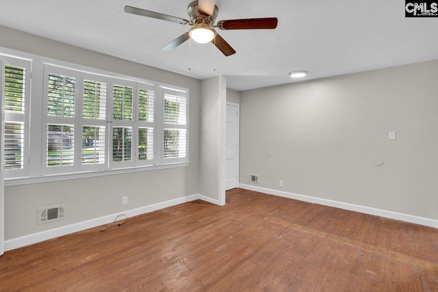spare room with wood finished floors, visible vents, baseboards, and a ceiling fan