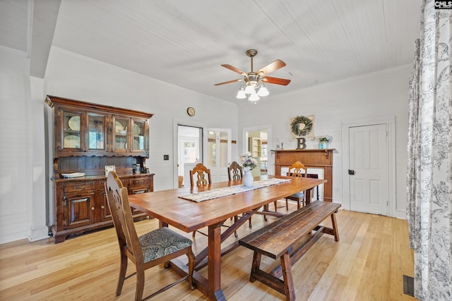 dining area with light wood finished floors, ornamental molding, a ceiling fan, and visible vents