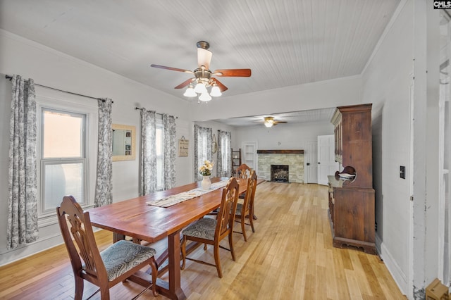 dining area with ornamental molding, a fireplace, light wood-style flooring, and ceiling fan