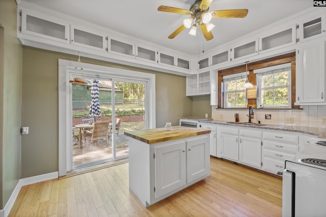 kitchen with a sink, tasteful backsplash, ceiling fan, white cabinets, and electric stove