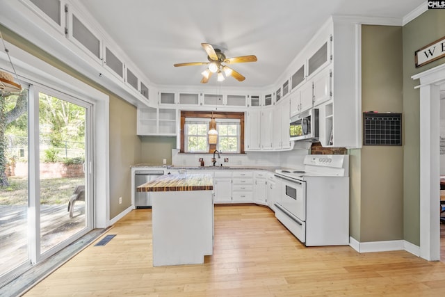 kitchen with a sink, stainless steel appliances, light wood finished floors, a ceiling fan, and wooden counters